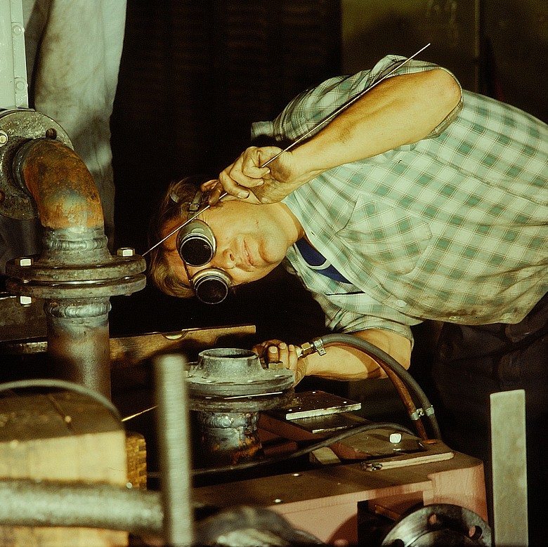 A craftsperson performs precision work on a metal installation